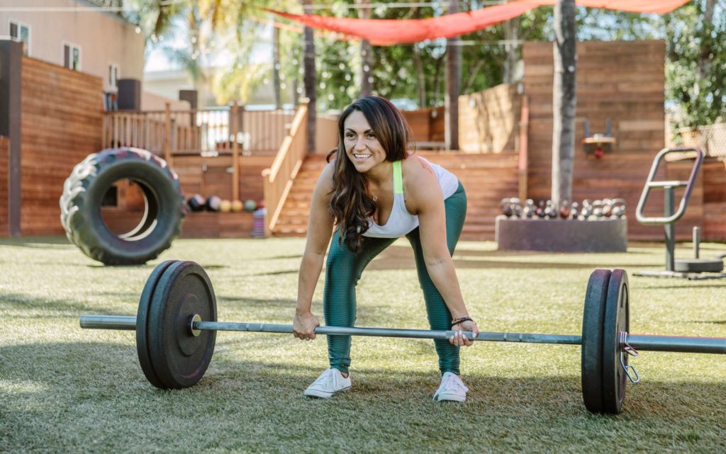 Gabby Lifting a large barbell in the training yard